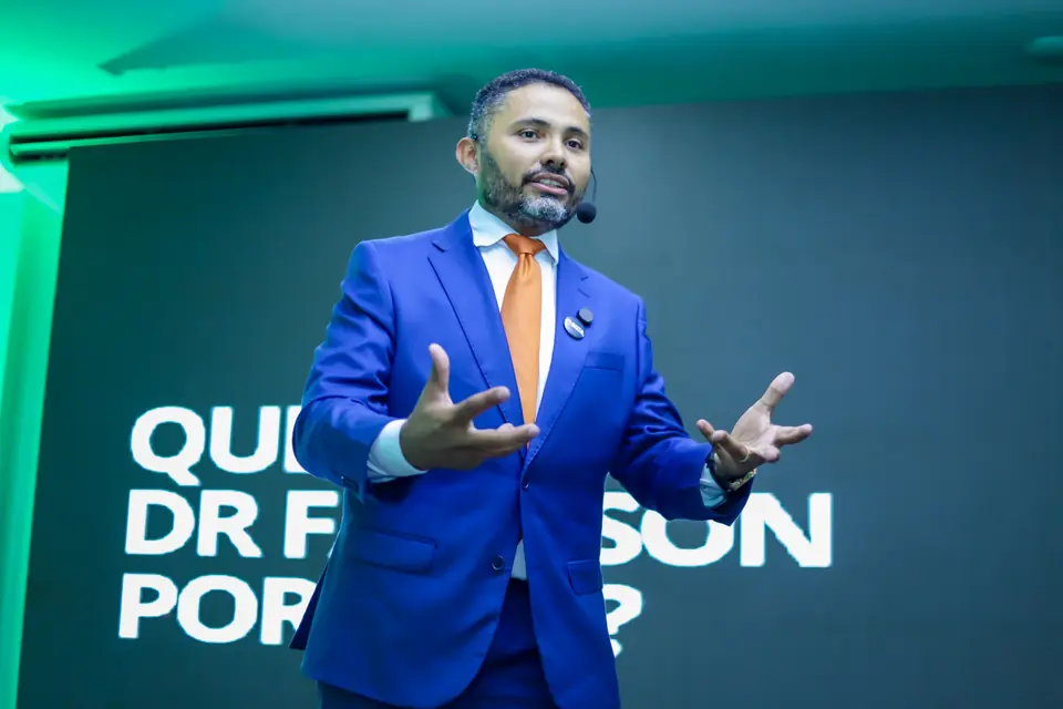 Dr. Fabilson Portela de braços abertos no palco, diante do telão