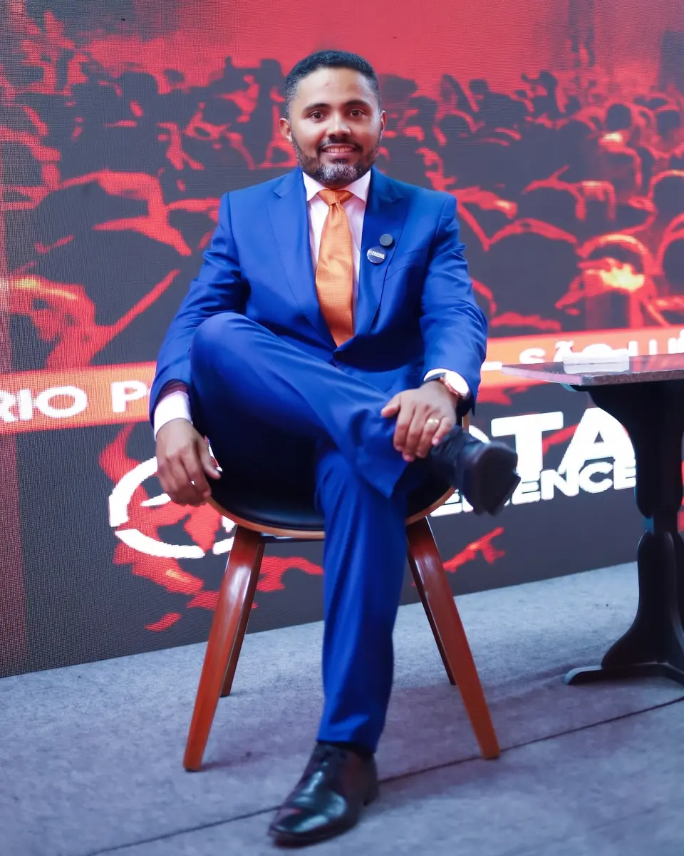 Dr. Fabilson Portela sentado no palco, diante do painel do ROTA EXPERIENCE